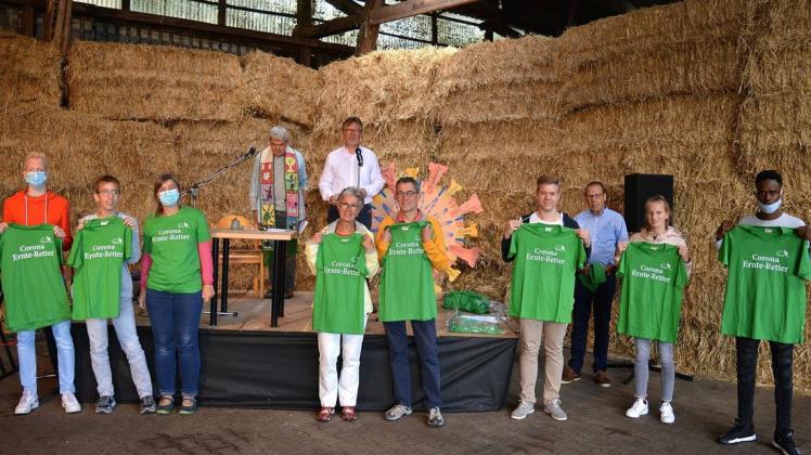 Zur Erinnerung an die Unterstützung im Corona-Lockdown überreichte der Ökohof den Helfern ein grünes T-Shirt mit der Aufschrift „Corona Ernte-Retter“. In der Mitte im Hintergrund Pastor Gerrit Weusthof (links) und Vorsitzender Hans-Bernd Eissing.