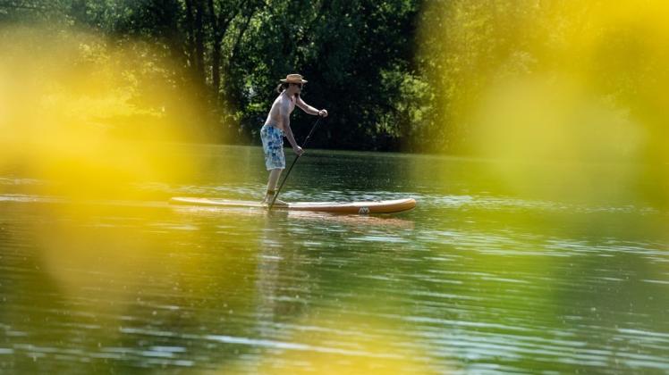 Mit einem Stand-up-Paddle-Board ist Dennis aus Göttingen auf dem Wendebach-Stausee unterwegs. Foto: Swen Pförtner/dpa