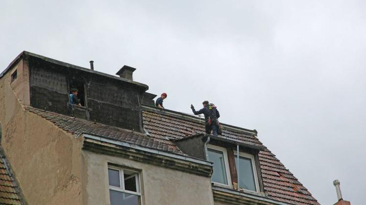 Ein Höhenretter steht auf einem Hausdach und hält den Sechsjährigen auf dem Arm.