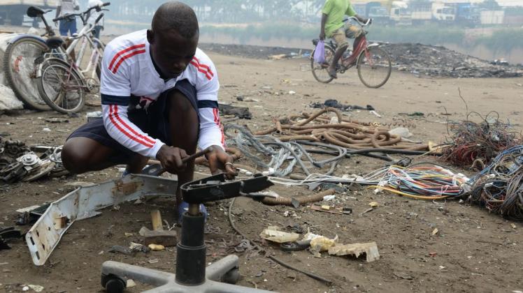 Der Recycler Lubman Idris nimmt vor seiner Werkstatt in Agbogbloshie (Ghana) ein altes Elektrogerät auseinander, um die Kupferspule darin zu gewinnen und diese weiterzuverkaufen.