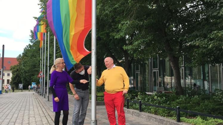 Vor dem Rostocker Rathaus hissen Bürgerschaftspräsidentin Regine Lück (Linke) sowie Max Rentner und 	Eckhard Brickenkamp (r.) vom CSD Verein die Regenbogenflagge. Sie wird bis zum CSD am 18. Juli wehen.