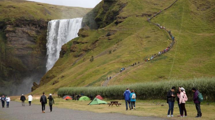Touristen spazieren am Wasserfall Skogafoss vorbei. Jahrelang sind die Touristenzahlen auf Island in die Höhe geschossen.