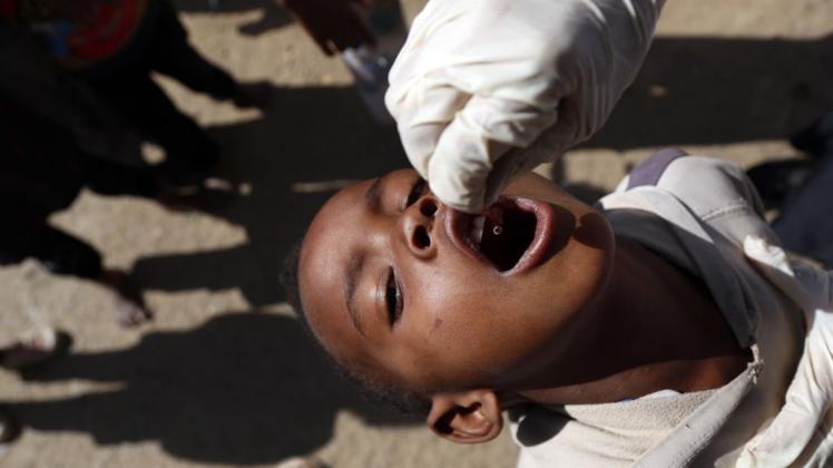 Ein Kind bekommt von einem Gesundheitshelfer den Polio-Impfstoff verabreicht.