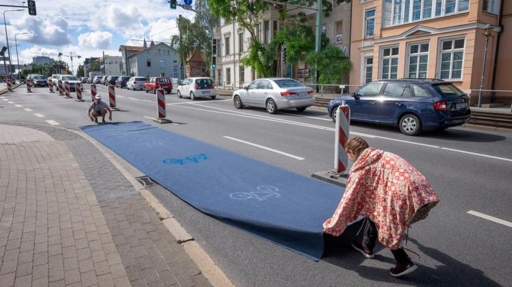 Richten die Pop-up-Bilke-Lane in der Ernst-Barlach-Straße ein: Julia Feßer und Henri Kassulis rollen einen blauen Teppich für Rostocks Radfahrer aus.
Foto: Georg Scharnweber