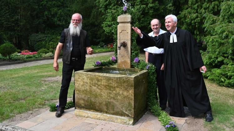 Für frische Wasserspritzer sorgt Pastor Bernd Schreinecke-von Clausewitz bei der Einweihung des Brunnens. Unser Bild zeigt ihn mit Klaus Schlüwe (links) und Friedhofsmitarbeiter Hermann Meese.