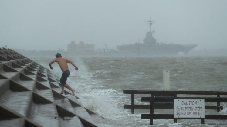 Ein Mann springt vor einer Welle zurück als Hurrikan "Hanna" auf die Küste trifft.