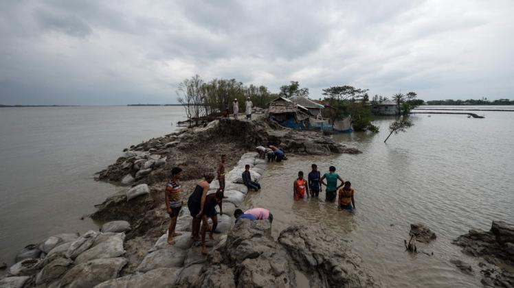 Freiwillige und Anwohner versuchen in Burigolini, Bangladesch, einen durchbrochenen Damm zu reparieren.
