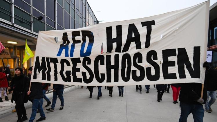 Teilnehmer einer Demonstration halten ein Banner mit der Aufschrift "AFD hat mitgeschossen" in die Höhe. Foto: dpa/Nicolas Armer