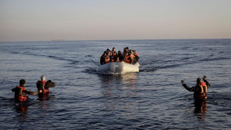 Freiwillige Helfer nehmen auf der griechischen Lesbos ein kaum seetüchtiges Gummiboot mit Flüchtlingen aus der Türkei in Empfang. Foto: picture alliance/Socrates Baltagiannis/dpa/dpa