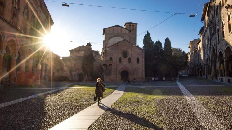 Bologna am Mittwoch: Eine Frau mit Mundschutz geht an der Basilika Santo Stefano vorbei. Viele Italiener bleiben mittlerweile zu Hause. Foto: Massimo Paolone/LaPresse/dpa