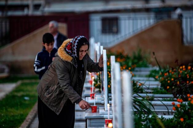 Eine Frau zündet eine Kerze an auf einem Grab eines Kämpfers der Demokratischen Kräfte Syriens (SDF) in Qamishli im Nordosten Syrien. 