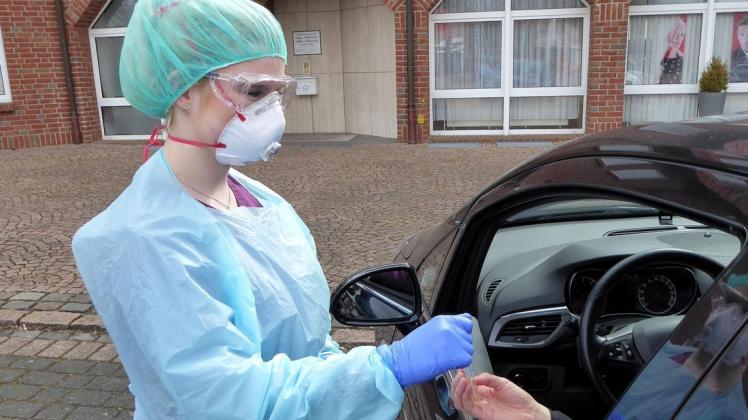Bei Coronaverdacht übergibt Maria Syring vom Praxisteam Wilmering in kompletter Schutzmontur auf dem Marktplatz einem Patienten ein Teststäbchen. Foto: Ursula Holtgrewe Bei Coronaverdacht übergibt Maria Syring vom Praxisteam Wilmering in kompletter Schutzmontur auf dem Marktplatz einem Patienten ein Teststäbchen. Foto: Ursula Holtgrewe