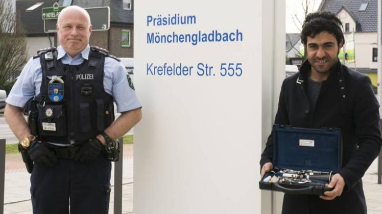 Polizeihauptkommissar Heiko Lammertz übergibt die Klarinette an Kisra Said Hassan. Foto: Polizei Mönchengladbach