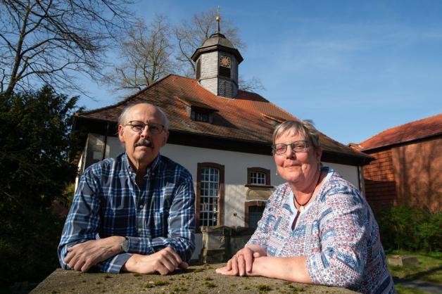 Das Ehepaar Uwe Kamm (SPD), stellvertretender Bürgermeister, und Roswitha Kamm, Kirchenvorsteherin, stehen vor der Kirche Löwenhagen mit ihrem kleinen Kirchturm.