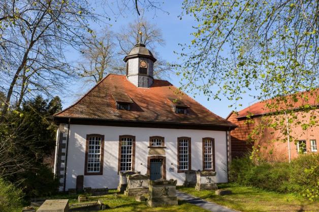 Außenaufnahme der Kirche Löwenhagen mit ihrem kleinen Kirchturm und einem alten Friedhof vor dem Eingang. 