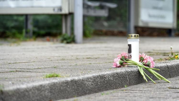 Eine Kerze und Blumen liegen an einer Haltestelle an der in der Nacht ein 14 Jahre alter Junge erstochen wurde.