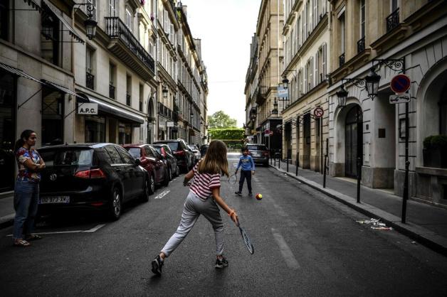 Kinder spielen auf einer leeren Straße in Paris Tennis.