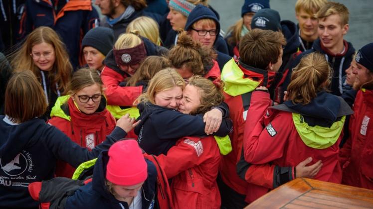 Erleichterte Jugendliche umarmen sich nach der Ankunft im Kieler Hafen auf dem Hauptdeck des Segelschiffes "Thor Heyerdahl".
