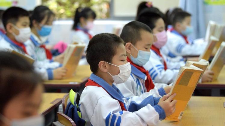 In der alten Kaiserstadt Xian tragen die Schüler lediglich Mundschutz (Foto). In Hangzhou waren Eltern und Schüler kreativ.