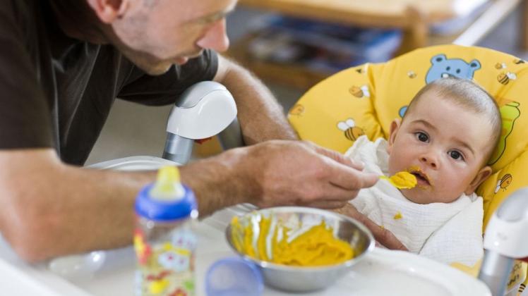 Ein Vater füttert seinen Sohn mit Brei. Immer mehr Väter nehmen sich eine Auszeit vom Job, um für ihre Kinder da zu sein. Symbolfoto:  Patrick Pleul/dpa