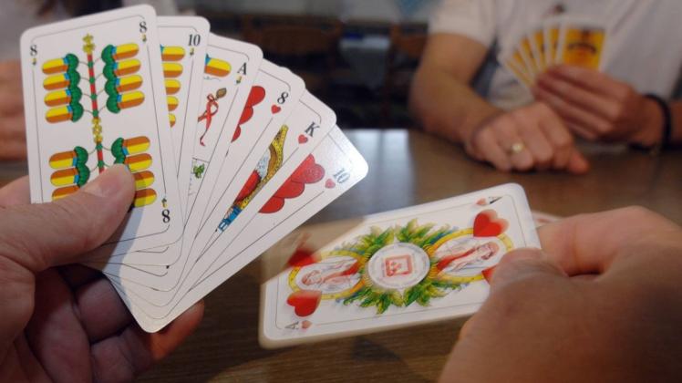Ein Kartenspieler hält Schafkopf-Spielkarten in der Hand. Foto: dpa/Armin Weigel