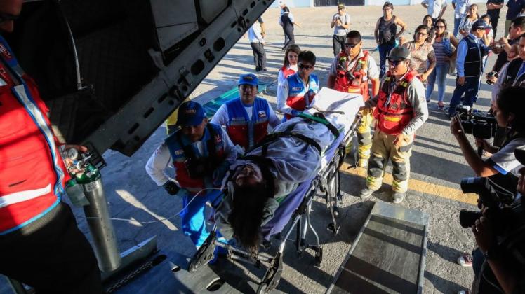Eine verletzte Frau wird in ein Flugzeug gebracht, um in ein Krankenhaus geflogen zu werden. Foto: Juan Carlos Guzman/Agentur Andina/dpa