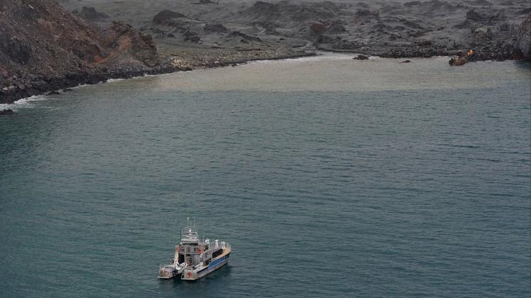 Retter suchen die Vulkaninsel nach den Vermissten ab – an Land (oben rechts) und im Wasser. Foto: imago images/ZUMA Press/New Zealand Defense