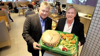 Bürgermeister Axel Wiechmann (l.) und Franchise-Nehmer Joachim Fietz feiern die Eröffnung mit einer McMenü-Torte.