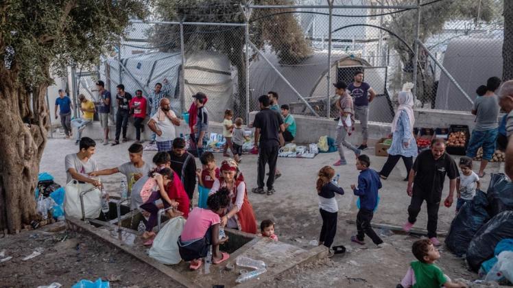 Migranten stehen um eine Wasserstelle und befüllen Flaschen im Flüchtlingslager Moria auf der griechischen Insel Lesbos. Foto: dpa/Angelos Tzortzinis