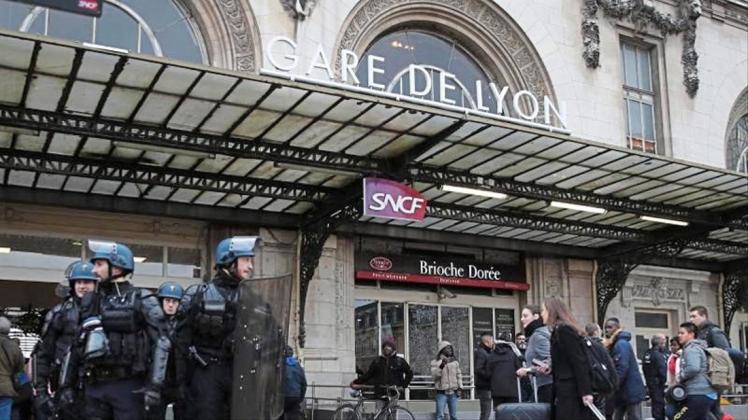 Reisende am Gare de Lyon, der während einer Demonstration der streikenden Eisenbahner von Polizisten bewacht wird. 