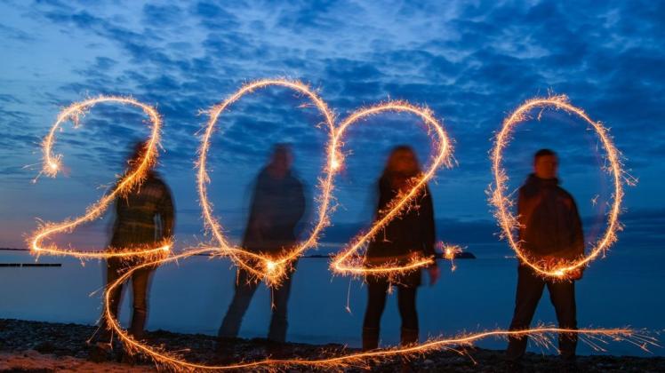 Vier Personen schreiben mit Wunderkerzen die Jahreszahl 2020 am Stand der Ostseeinsel Rügen in den Abendhimmel. Foto: Patrick Pleul/dpa Vier Personen schreiben mit Wunderkerzen die Jahreszahl 2020 am Stand der Ostseeinsel Rügen in den Abendhimmel. Foto: Patrick Pleul/dpa