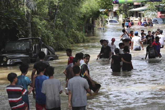 Bewohner einer überfluteten Nachbarschaft im indoseischen Tangerang gehen durch das Hochwasser.