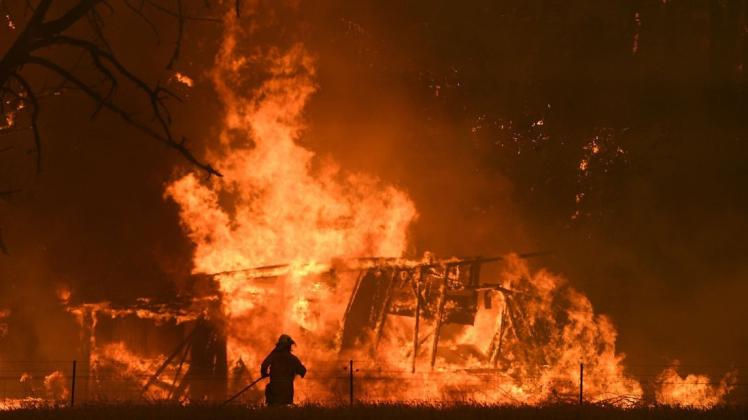 21.12.2019: Ein Feuerwehrmann bekämpft die Flammen des «Gosper Mountain»-Feuers, die ein Gebäude erreicht haben. Foto: dpa/Dan Himbrechts