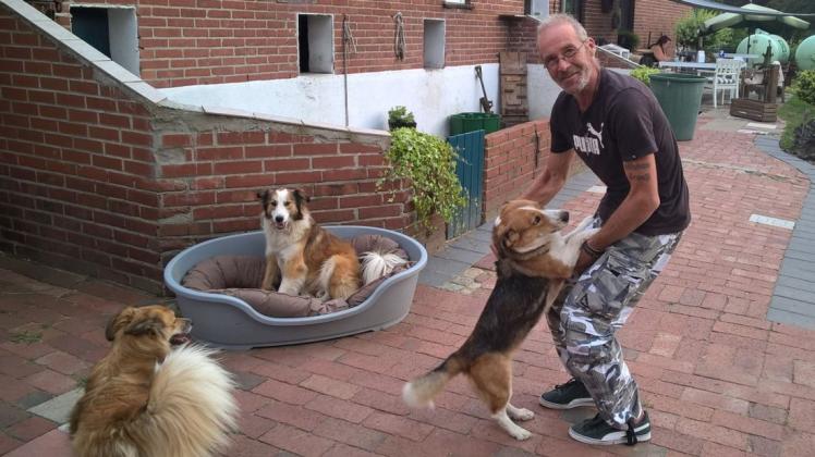 Uwe Hammes mit drei seiner sechs Hunde. Lieschen springt gerade an seinem Herrchen hoch. Foto: Andreas Bahlmann