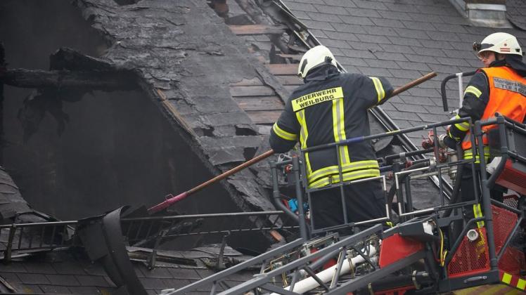Feuerwehrleute sind nach dem Wohnhausbrand im Ortskern mit Nachlöscharbeiten beschäftigt. Foto: dpa/Thomas Frey