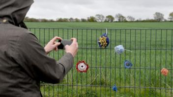 Gehäkelte Blumen hängen am Wildschweinzaun an der deutsch-dänischen Grenze. Foto: Carsten Rehder/dpa