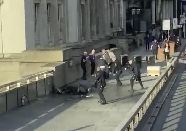 Ein Videostill, das von dem Twitteraccount @HLOBlog zur Verfügung gestellt wurde. Auf der London Bridge umstellen bewaffnete Polizisten einen auf dem Boden liegenden Mann. Foto: @HLOBlog/AP