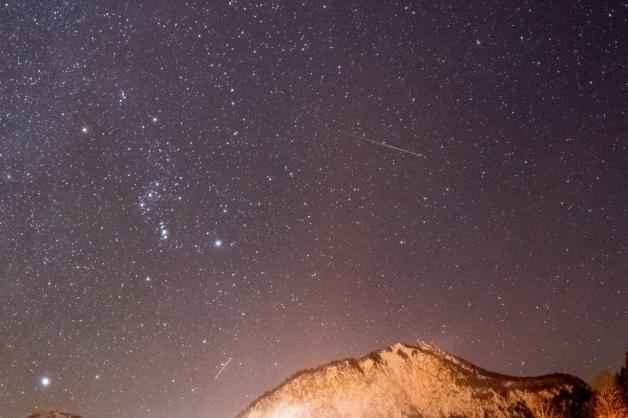 Eine Sternschnuppe der Geminiden über den Bergen der Oberstdorfer Alpen. Foto: imago images/Jan Eifert