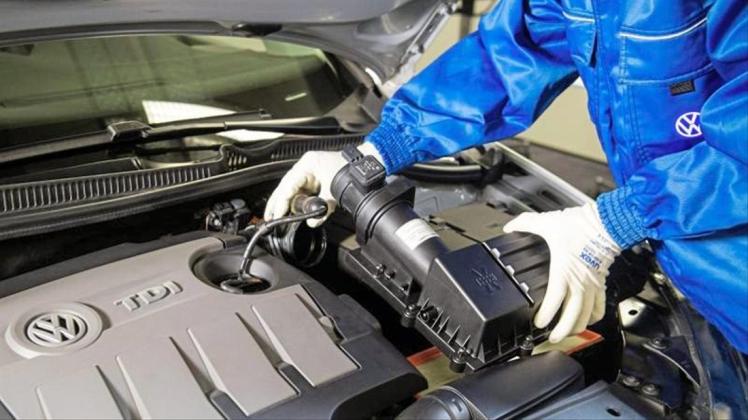Ein VW-Mitarbeiter baut einen um einen Strömungsgleichrichter erweiterten Luftfilter in einen Dieselmotor der Typreihe EA 189 ein. 