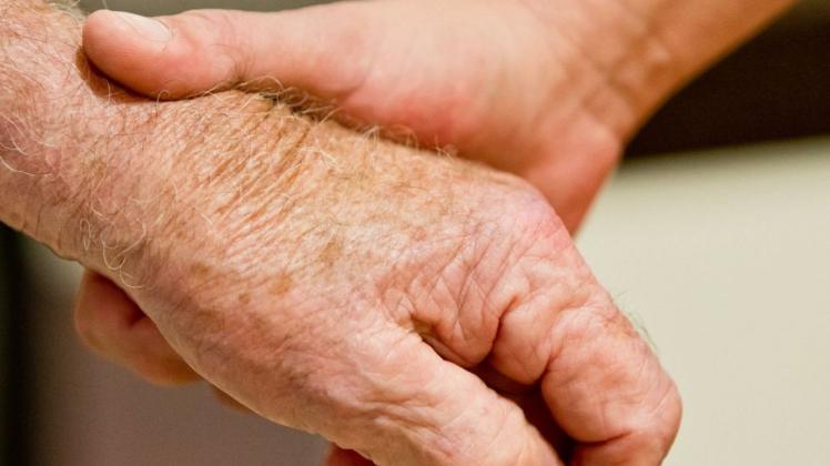 Eine auf Demenzkranke spezialisierte Altenpflegerin (r) hält die Hand eines demenzkranken Mannes.  Foto: Daniel Karmann/dpa