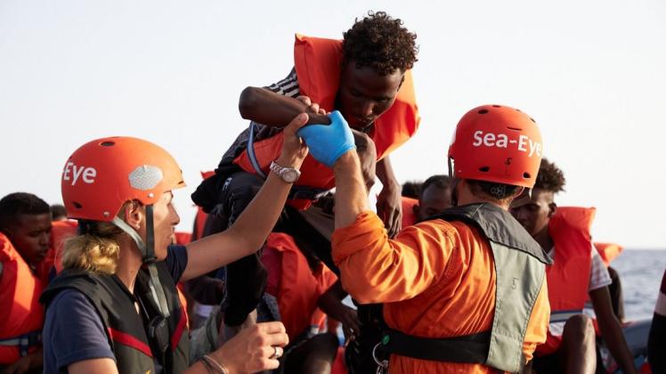 Mittelmeer: Die von der Seenotrettungsorganisation Sea-Eye herausgegebene Aufnahme zeigt Seenotretter, die Flüchtlinge im Mittelmeer von einem Schlauchboot evakuieren. Foto: Fabian Heinz/Sea-Eye/dpa