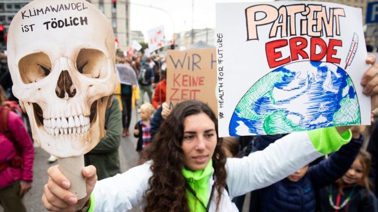 In Hamburg zeigte diese Demonstrantin Transparente mit der Aufschrift "Klimawandel ist tödlich" und "Patient Erde" Foto: Christian Charisius/dpa