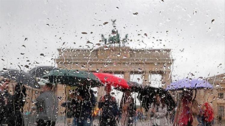 Passanten laufen bei Regen über den Pariser Platz vor dem Brandenburger Tor in Berlin. Nach Angaben der Meteorologen wird auch in den kommenden Tagen immer wieder mit Regenschauern zu rechnen sein. 