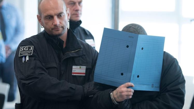 Beim Prozessauftakt in Dresden verbirgt einer der Angeklagten sein Gesicht. Mitglieder der mutmaßlichen Terrorgruppe "Revolution Chemnitz" sollen tödliche Angriffe geplant haben.  Foto: Sebastian Kahnert / POOL / AFP