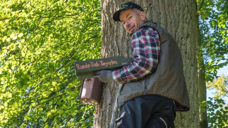 Andreas Kinder (Runder-Tisch-Tiergarten) hängt einen der neuen Fledermauskästen an einen Baum. Carola Schewe-Kinder