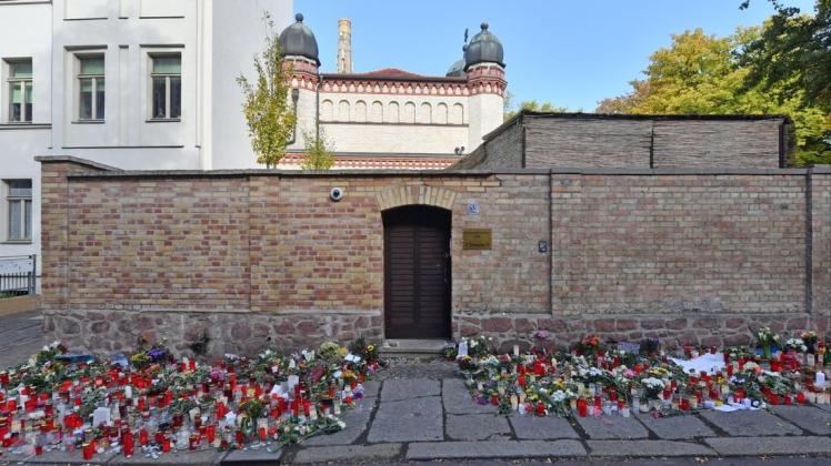 Blumen und Kerzen stehen neben der Tür zur Synagoge in Halle nach dem rechtsterroristischen Anschlag. Foto: dpa/Hendrik Schmidt