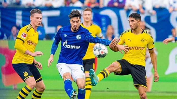 Dortmunds Achraf Hakimi (r) und Lukasz Piszczek (l) nehmen Schalkes Suat Serdar in die Zange. 