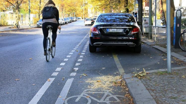 Falschparker sind ein Gefahr – wie hier, wo das Auto die Radfahrerin auf die Fahrbahn zwingt. Foto: imago images/Andreas Gora