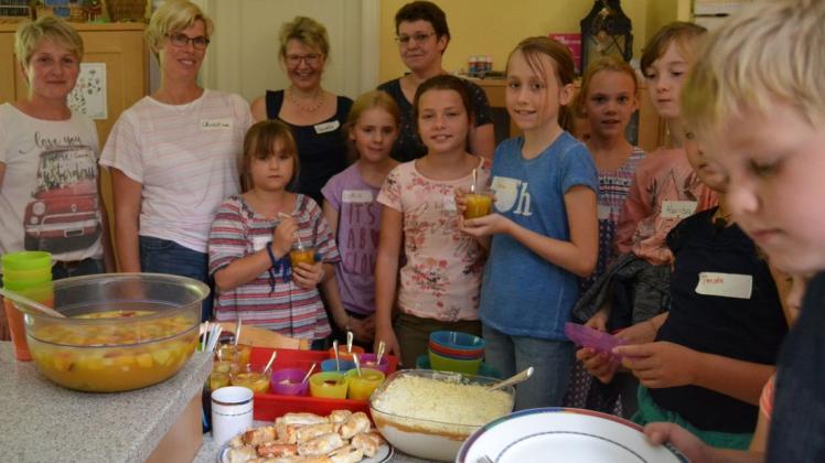 Ferienspaß auf dem Hof Schwarting: Die Ganderkeseer Landfrauen und die Kinder am selbst gefertigten Mittagsbüfett. Foto: Reiner Haase