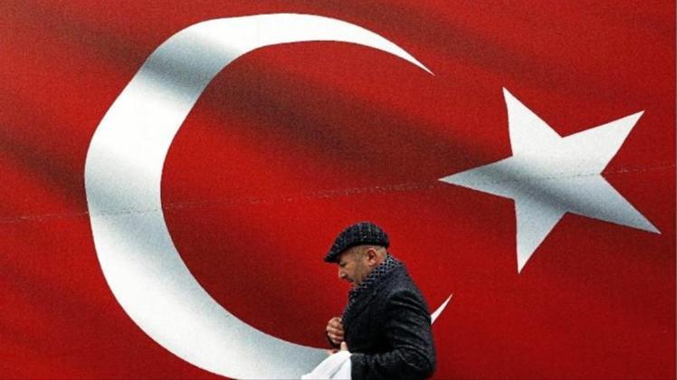 Ein Mann geht an einer türkischen Flagge vorbei. 